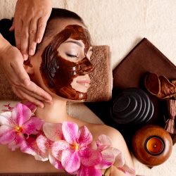 Spa massage for young woman with facial mask on face - indoors